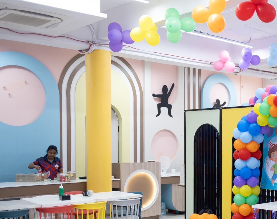 Pastel party room at Baccha Party Matunga with balloon garlands across the ceiling and café seating ready for a birthday