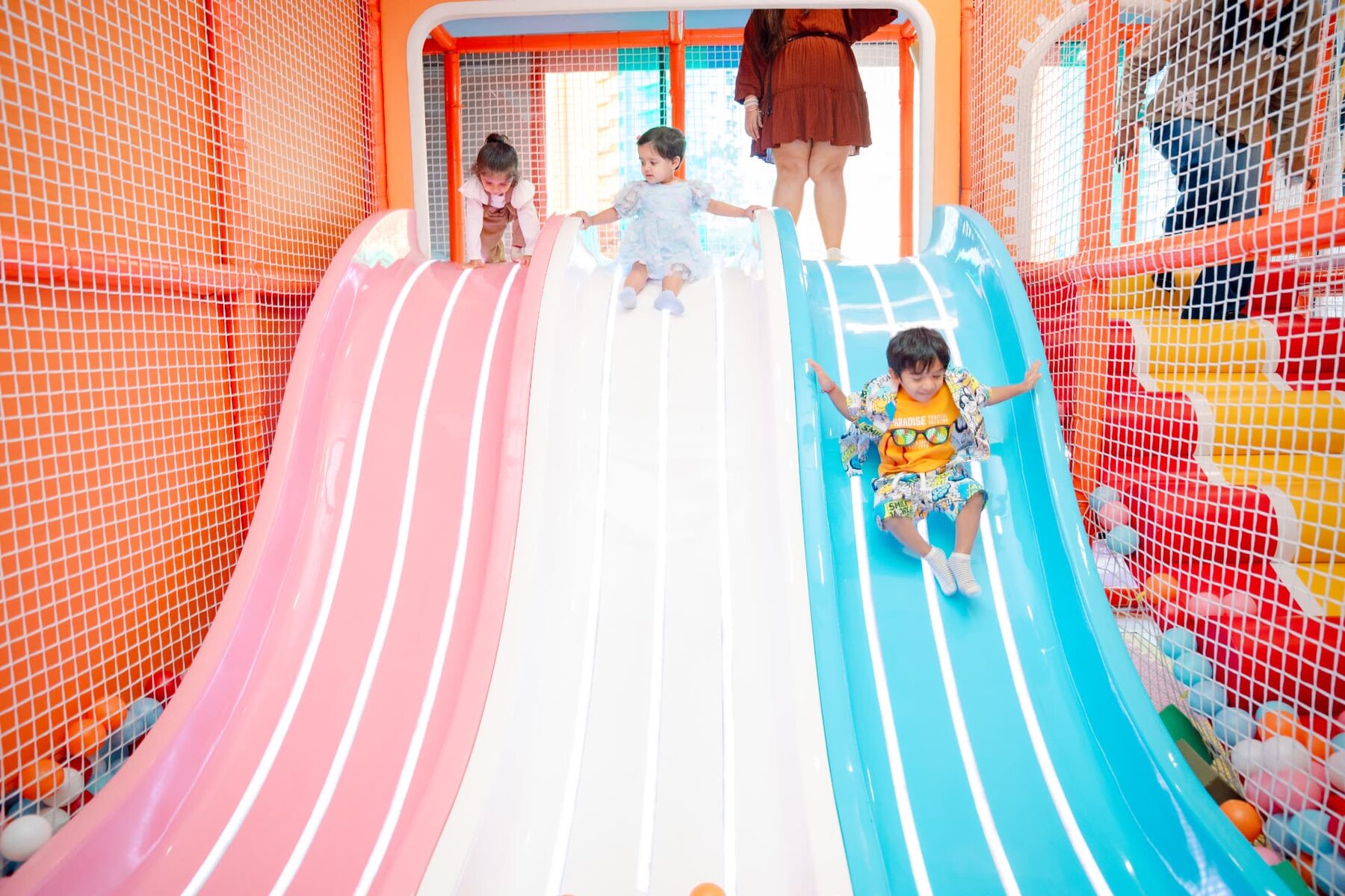 Children sliding down the pink, white and blue wave slides at Baccha Party Powai